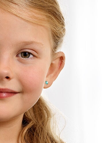 Child smiling and posing with Blomdahl Singapore hypoallergenic earrings. Blomdahl earrings are hypoallergenic and suitable for sensitive skin and children